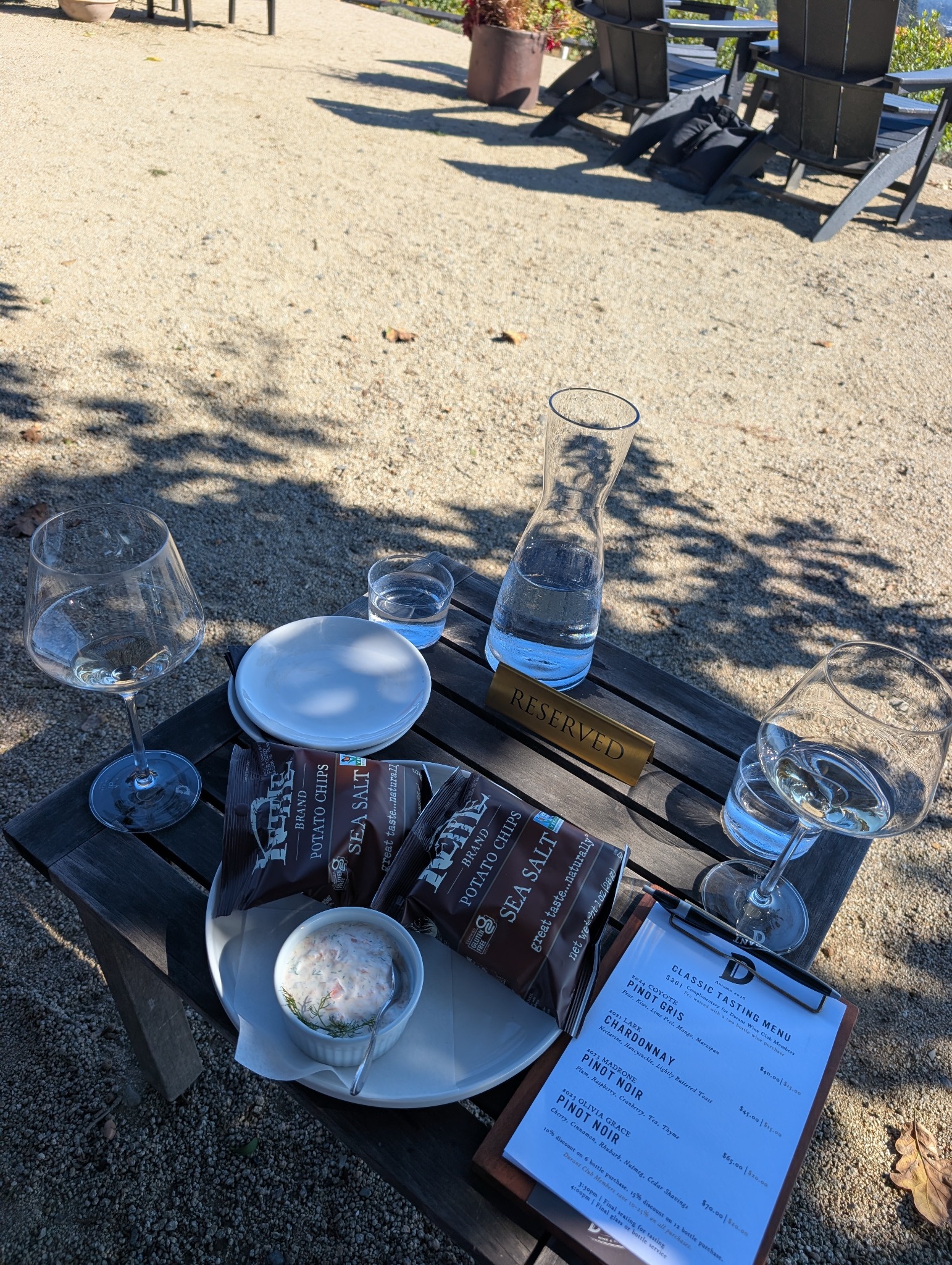Wine glasses, smoked salmon dip, chips, and a tasting menu on an outdoor table at Durant